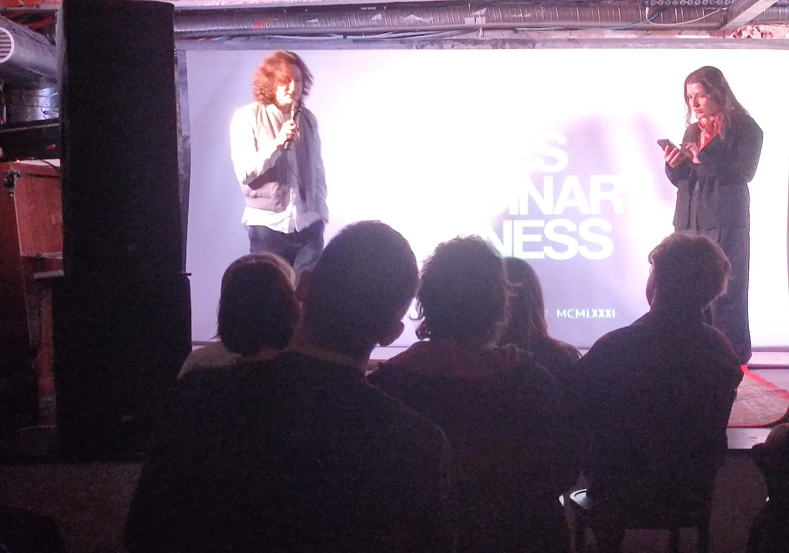 Presenters and audience in front of a projection screen at the 2025 event.