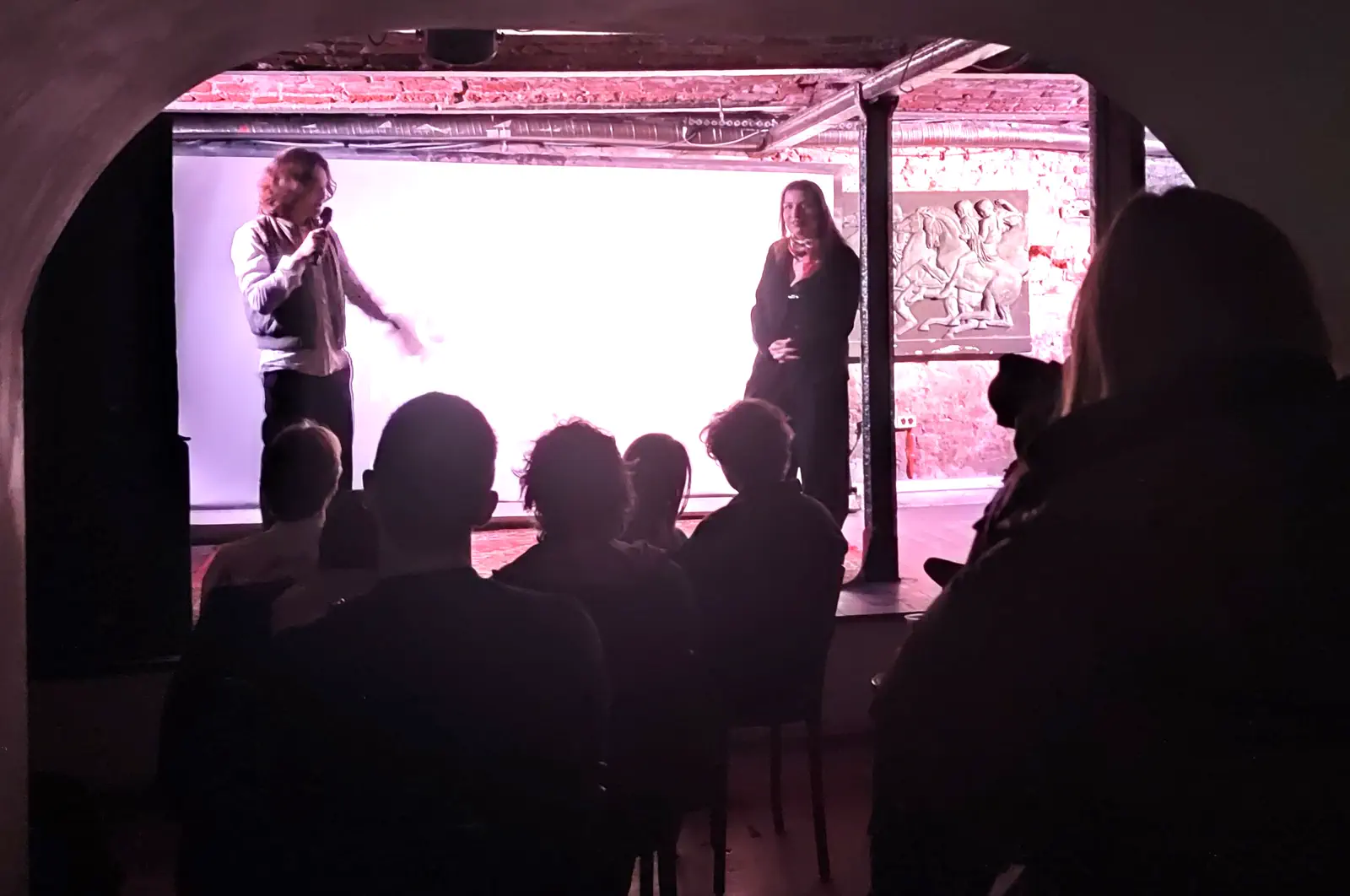 Audience watching two presenters on stage during the 2025 event.